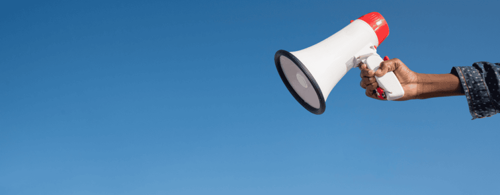 A person holding a megaphone against a clear blue sky, symbolizing outreach and amplification—core themes in B2B lead generation.